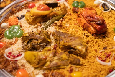 Delicious healthy food recipes, a rich breakfast with a variety of dishes and appetizers, a metal tray filled with rice and spices, a plate of rice garnished with stuffed chicken.