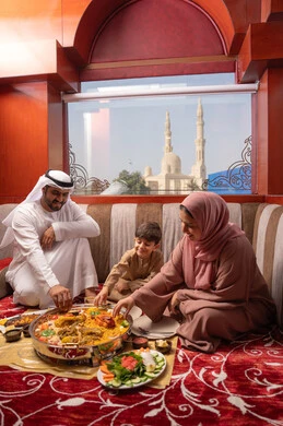 Ramadan iftar includes a variety of dishes and delicious appetizers, restaurants and cafes in the United Arab Emirates, an Emirati Gulf Arab family dressed in traditional attire sitting in a popular ground seating area around the dining table.