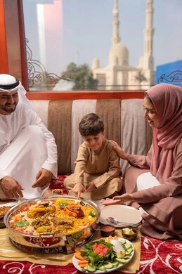 The Ramadan iftar table with a variety of delicious dishes, restaurants and cafes in the United Arab Emirates, an Emirati Gulf Arab family dressed in traditional attire sitting in a popular family gathering around the dining table.