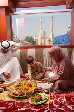 Ramadan iftar is rich with delicious foods and appetizers, restaurants and cafes in the United Arab Emirates, an Emirati Gulf Arab family dressed in traditional attire sitting in a popular ground seating area of the family around the dining table.