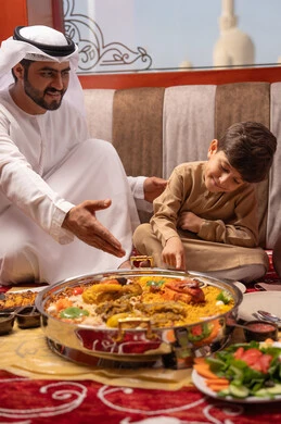 A Ramadan iftar table filled with delicious dishes and various appetizers, restaurants and cafes in the United Arab Emirates, an Emirati Gulf Arab family dressed in traditional attire sitting in a popular family gathering around the dining table.