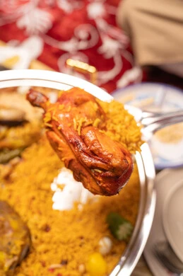 A metal tray filled with rice and spices, dishes of traditional popular Arabic cuisine, a close-up image of a plate of rice garnished with stuffed chicken, delicious healthy food recipes.