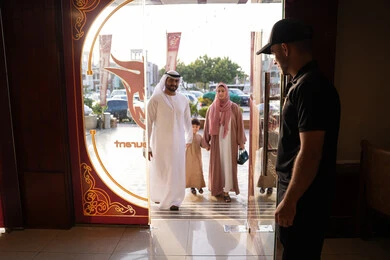 لحظات دخول عائلة عربية خليجية اماراتية إلى المطعم، رجل عربي خليجي اماراتي يرتدي الكندورة و الدشداشة يسير برفقه زوجته و ابنة بايماءات السعادة و السرور، قضاء الأوقات الممتعة مع الأبناء
