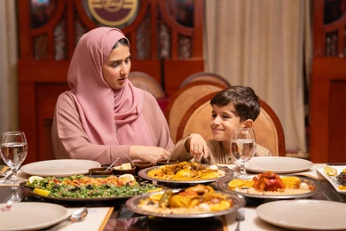 شهر الخير والبركة ، المأكولات والمقبلات الشهية، اجتماع الاسرة حول مائدة الطعام ، أجواء أسرية مليئة بالحب، نقاشات وحوارات عائلية، مائدة طعام مليئة بالوجبات الرمضانية المتنوعة، الأعياد والمناسبات الاسلامية، ام عربيه خليجيه اماراتيةترتدي العباءة و الحجاب تقوم بتناول الافطار برفقة ابنها