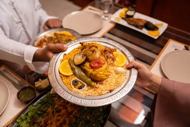 وجبة افطار ملئية بأصناف من المأكولات العربية الاماراتية الذيذة الرمضانية على طاولة الطعام ، صورة مقربة ليد عائلة عربية خليجية اماراتية  تتناول طعام الافطار ، المناسبات الاسلامية و الدينية