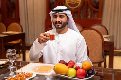 احتساء مشروب ساخن داخل الكافيه ، الاستمتاع بالأنشطة الترفيهية، قضاء أوقات ممتعة في المقهى، تعابير السرور والسعادة، رجل عربي خليجي اماراتي يرتدي الكندورة و الغتره يجلس على الطاولة يمسك بيدية كوب من الشاي , مطاعم و كافيهات في الإمارات العربية المتحدة احتساء مشروب ساخن داخل الكافيه ، الاستمتاع بالأنشطة الترفيهية، قضاء أوقات ممتعة في المقهى، تعابير السرور والسعادة، رجل عربي خليجي اماراتي يرتدي الكندورة و الغتره يجلس على الطاولة يمسك بيدية كوب من الشاي , مطاعم و كافيهات في الإمارات العربية المتحدة