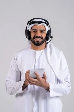 The concept of customer service, gestures of happiness and joy, monitoring and developing work, documenting and recording notes and complaints, a portrait of an Emirati Gulf Arab employee wearing a kandura and ghutrah, wearing headphones on his head, writing on papers, responding to inquiries and questions, white background.