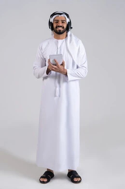 ايماءات السعادة و السرور، متابعة وتطوير العمل، مفهوم خدمة العملاء، تدوين و تسجيل الملاحظات و الشكاوي، بورتريه لموظف عربي خليجي اماراتي يضع الكندورة و الغتره يضع سماعات الهيدفون على رأسها يقوم  بالكتابة على الاوراق، الرد على الاستفسارت والتساؤولات، الجسم بالطول الكامل، خلفية بيضاء