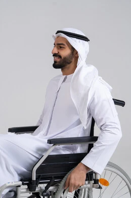 تسهيل الحركة والتنقل عبر الأجهزة والمعدات، شعور المعاقين بالإنتماء والتقدير والإحترام في الامارات العربيه، بورتريه من الجانب لرجل عربي اماراتي خليجي من ذوي الاحتياجات الخاصه يجلس على كرسي متحرك، خلفيه بيضاء