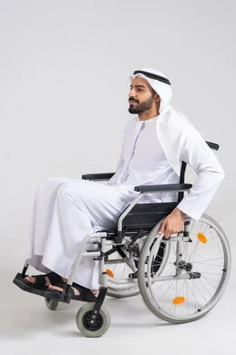 The feeling of belonging, appreciation, and respect for the disabled in the United Arab Emirates, providing devices and equipment that assist with movement and mobility, a side portrait of an Emirati Arab man with special needs sitting in a wheelchair, with a white background.
