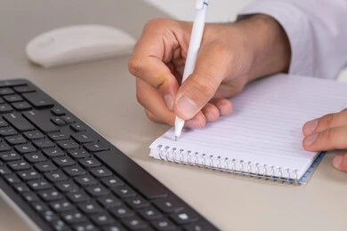 ادارة المهام وتنظيم الأعمال، التخطيط اليومي وإدارة الوقت, صورة مقربة ليد شاب عربي خليجي اماراتي يرتدي الثوب التقليدي يقوم بكتابة الملاحظات والأهداف اليومية