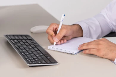 Daily planning and time management, task management and organizing work, a close-up image of the hand of a young Arab Gulf Emirati man wearing traditional attire writing notes and daily goals.