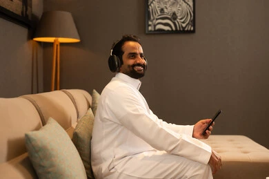 الاستماع إلى الموسيقى والتسجيلات الصوتية، الاستفادة من الجوال والأجهزة التكنولوجية، رجل عربي خليجي سعودي يرتدي الثوب الابيض يجلس فى غرفه المعيشة يرتدي سماعة الرأس بإيماءات السعادة, استخدام الهاتف و تقنية الهيدفون الاستماع إلى الموسيقى والتسجيلات الصوتية، الاستفادة من الجوال والأجهزة التكنولوجية، رجل عربي خليجي سعودي يرتدي الثوب الابيض يجلس فى غرفه المعيشة يرتدي سماعة الرأس بإيماءات السعادة, استخدام الهاتف و تقنية الهيدفون