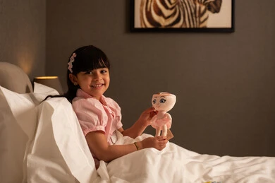 ايماءات السعادة و السرور، ممارسة نشاط ترفيهي مسلي، فتاه عربيه خليجي سعودية ترتدي الزي الكاجوال تجلس على السرير فى غرفه النوم تمسك بيديه لعبه