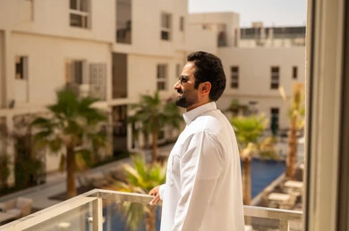 الاهتمام بالمظهر الخارجي والأناقة، مفهوم الرجولة والثقة بالنفس،  رجل عربي خليجي سعودي يرتدي الثوب الابيض و النظارة الشمسية  ينظر بتعابير السرور، الوقوف باستقامة وثبات