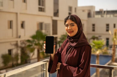 عرض شاشة سوداء عبر الجوال ، قضاء وقت ممتع فى الخارج ، امراه عربيه خليجيه سعودية محجبة ترتدي العباءة تمسك بيديها الهاتف المحمول، النظر بتعابير السعادة و السرور