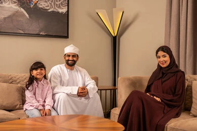 ايماءات تدل على الفرح و السعادة, الإهتمام والاعتناء بالأبناء, أجواء عائليه مليئة بالحب, أم عربيه سعوديه خليجيه تجلس في غرفة المعيشة برفقة ابنتها وزوجها, قضاء أوقات ممتعه مع العائلة