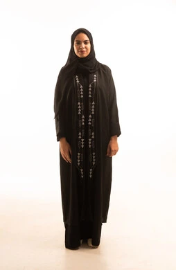 Interest in fashion and elegance, the concept of caring for one's appearance, a portrait of a smiling Saudi Gulf Arab woman wearing a black abaya and hijab, standing with crossed arms, gestures of pride and dignity, looking at the camera, white background.