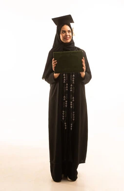 الاحتفال بإنهاء الدراسة الجامعية، بورتريه لخريجة عربية خليجية سعودية محجبة ترتديعباءة سوداء والقبعة تحمل بيدها الشهادة، النجاح والتفوق والتخرج من الجامعة، إيماءات السعادة بالوصول الى الحلم، خلفية بيضاء