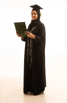 النجاح والتفوق والتخرج من الجامعة، إيماءات السعادة بالوصول الى الحلم، الاحتفال بإنهاء الدراسة الجامعية، بورتريه لخريجة عربية خليجية سعودية محجبة ترتديعباءة سوداء والقبعة تحمل بيدها الشهادة، خلفية بيضاء