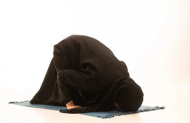 بورتريه لإمرأة عربية خليجية سعودية ترتدي الحجاب والعباءة السوداء تسجد على سجادة الصلاة,  التقرب الى الله من خلال الإجتهاد في العبادة والحفاظ على الصلاه، أداء الفروض على وقتها, خلفية بيضاء