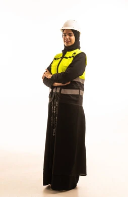 مفهوم الهندسه المعماريه، بورتريه لمهندسة معمارية عربية خليجية سعودية محجبة مبتسمه تقف بأيدى متقاطعة ترتدي بدلة وخوذة السلامة في العمل, مهن ووظائف هندسيه، النظر الى الكاميرا, الجسم بالطول الكامل، خلفية بيضاء