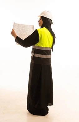 تقدم وتطور السعودية على يد نساء الوطن, بورتريه من الخلف لمهندسة عربية خليجية سعودية مبتسمة محجبة ترتدي الخوذة وسترة الحماية تمسك مخطط الإعمار, الهندسة والانشاء المعماري, الاهتمام بشؤون العمل, تدقيق مخطط الإنشاء, خلفية بيضاء