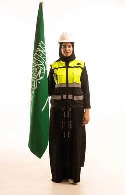النظر الى الكاميرا بايماءات الفخر و الاعتزاز، بورتريه لمهندسة عربية خليجية سعودية محجبة ترتدي خوذة وسترة الحماية تحمل علم المملكة، الإحتفال بيوم العلم 11 مارس، الجسم بالطول الكامل، خلفية بيضاء