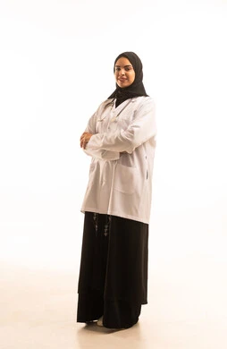 Standing with crossed arms, a portrait of an Arab Gulf Saudi female doctor wearing an abaya and hijab with a white coat and stethoscope, standing upright, looking with gestures of happiness and joy, the concept of medicine and healthcare, female professions and jobs, full-body, white background.