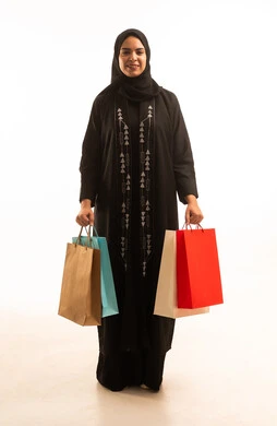 الاثر الايجابي للتسوق على نفسية المرأة, بورتريه لسيدة عربية خليجية سعودية محجبة ترتدي عباءة سوداء تحمل اكياس التسوق, صورة للجسم بالطول الكامل , خلفية بيضاء