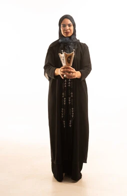 بورتريه لامرأة عربية خليجية سعودية محجبة ترتدي العباءة السوداء تمسك المبخرة التراثية المزخرفة بيدها تنظر الى الكاميرا، استخدام خشب العود للتطيب, أصالة العادات والتقاليد الخليجية, منتج محلي وطني, خلفية بيضاء