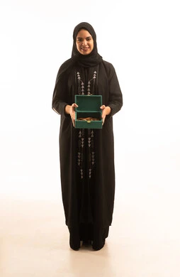 بورتريه لشابة عربية خليجية سعودية ترتدي العباءة السوداء تنظر الى الكاميرا تحمل بيدها صندوق من خشب العود،  ذكرى تأسيس الدولة السعودية الاولى 22 فبراير، يوم بدينا 1727 م، صورة الجسم بالطول الكامل، خلفية بيضاء