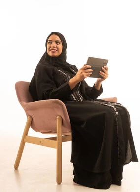 Looking at something, browsing social media, a portrait of a smiling Arab Gulf Saudi woman using a tablet, a remote work meeting, communicating with friends, white background.
