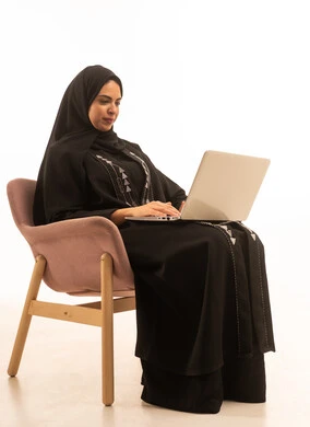 , إستخدام الحاسوب لإنجاز المهام، بورتريه لسيده عربيه خليجيه سعودية ترتدي العباءه السوداء  تحمل بيدها جهاز اللاب توب المحمول، تطور التكنولوجيا والأجهزة التقنية، خلفية بيضاء