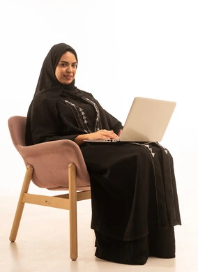 بورتريه لسيده عربيه خليجيه سعودية ترتدي العباءه السوداء تحمل بيدها جهاز اللاب توب المحمول، تطور التكنولوجيا والأجهزة التقنية, إستخدام الحاسوب لإنجاز المهام، خلفية بيضاء