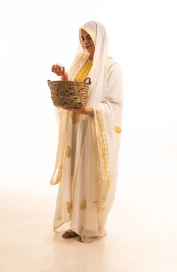 A side portrait of a smiling Saudi Arabian Gulf girl wearing a shayla and nashl, holding a wicker basket filled with natural damask roses. She is dressed in the traditional attire of the Eastern Province, showcasing old popular crafts and trades. It commemorates the founding of the Saudi state on February 22. The background is white, and it is a full-body image.