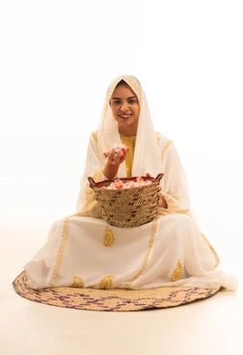 Local product and crop, anniversary of the establishment of the first Saudi state on February 22, a portrait of a young Arab Gulf Saudi woman wearing a white abaya sitting on a straw mat in front of a basket full of flowers, smiling at the camera, on the day we began in 1727 AD, white background.