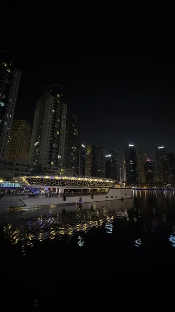 The growth and urban development of the illuminated financial towers of the Emirates at night, the buildings and commercial establishments in the United Arab Emirates, the architectural engineering art in the modern style of towers and skyscrapers, famous landmarks and tourist attractions in the city of Dubai, attracting and drawing tourists from around the world.