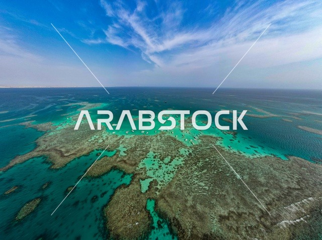 An aerial image of Sindala Island in the NEOM project in northwestern Saudi Arabia, with turquoise waters of the Red Sea surrounding the island with white beaches, attracting and drawing tourists from around the world. The modern design of Sindala resorts and yacht marinas, summer recreational activities, and a natural landscape that combines luxury and tranquility.