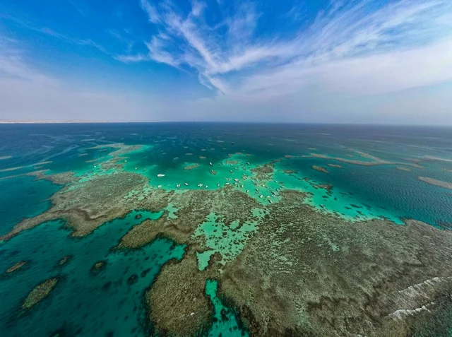 صورة جوية لجزيرة سندالة في مشروع نيوم شمال غرب السعودية، مياه البحر الأحمر الفيروزية تحيط بالجزيرة ذات الشواطئ البيضاء، جذب واستقطاب السياح من انحاء العالم ، التصميم العصري لمنتجعات سندالة ومراسي اليخوت، أنشطة صيفية ترفيهية، منظ طبيعي يجمع بين الفخامة والهدوء