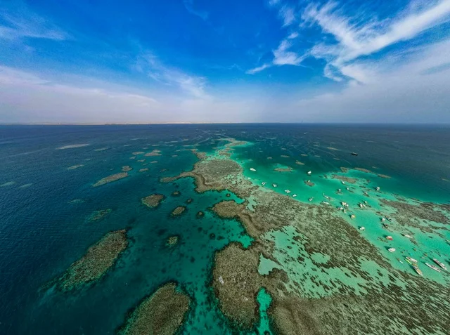صورة جوية لجزيرة سندالة في مشروع نيوم شمال غرب السعودية، مياه البحر الأحمر الفيروزية تحيط بالجزيرة ذات الشواطئ البيضاء، جذب واستقطاب السياح من انحاء العالم ، التصميم العصري لمنتجعات سندالة ومراسي اليخوت، أنشطة صيفية ترفيهية، منظ طبيعي يجمع بين الفخامة والهدوء