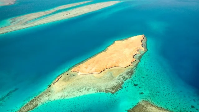 منظر طبيعي يجمع بين الفخامة والهدوء، أنشطة صيفية ترفيهية، التصميم العصري لمنتجعات سندالة ومراسي اليخوت،  جذب واستقطاب السياح من انحاء العالم ، مياه البحر الأحمر الفيروزية تحيط بالجزيرة ذات الشواطئ البيضاء، صورة جوية لجزيرة سندالة في مشروع نيوم شمال غرب السعودية