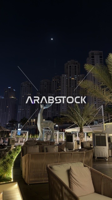 Commercial buildings and facilities in the United Arab Emirates, the growth and urban development of the brightly lit Emirates Towers at night, the architectural engineering art in the modern style of towers and skyscrapers, famous landmarks and tourist attractions in the city of Dubai, attracting and drawing tourists from around the world.