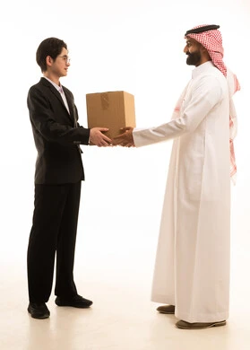 A portrait of a Saudi Gulf Arab man wearing traditional attire and a shemagh receiving a package, an Asian representative delivering a shopping box, the concept of online shopping and orders, an electronic purchasing process, fast delivery service, white background.