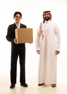 The concept of online shopping and online orders, an electronic purchasing process, fast delivery service, a portrait of a Gulf Arab Saudi man wearing traditional attire and a ghutrah receiving a package, an Asian courier delivering a shopping box, white background.