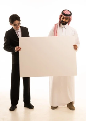 Using a blank billboard, a portrait of a Saudi Arabian Gulf man wearing traditional attire and a shemagh standing next to an Asian young man in a formal suit, both holding a large rectangular mock-up, a white explanatory board, full-body image, white background.