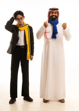 Encouraging the Saudi team, a portrait of an Arab Gulf Saudi man wearing traditional attire and a shemagh, raising his hands in expressions of victory, standing next to a young Asian man in a formal suit and a Nasr team scarf, placing his hand on his head with gestures of sadness, full-body, white background.