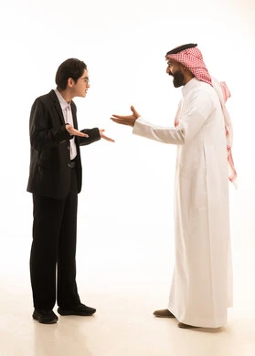 الشعور بالدهشة والصدمة والذهول, التفاجؤ من شيء ما، بورتريه لشاب اسيوى يرتدي البدلة الرسمية يرفع يديه بإيماءات الغضب والانفعال يقف امام رجل عربي خليجي سعودى يرتدى الثوب التقليدى والشماغ يرفع يديه بصدمة، الجسم بالطول الكامل، خلفية بيضاء