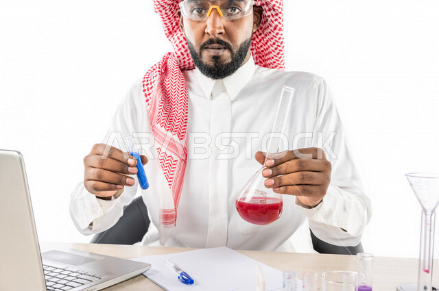 بورتريه لرجل خليجي سعودي ، بالزي السعودي التقليدي ، إستخدام جهاز الحاسوب المحمول، إستخدام انابيب الاختبار لإجراء التجارب، إجراء تجارب وتفاعلات كيميائية في المختبر، تجارب وأبحاث علمية، دراسات وتحاليل، خلفية بيضاء، مختبر ومعمل الكيمياء، البحث والتطوير