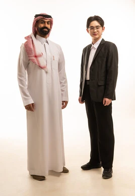 بورتريه لرجل اسيوى يرتدى البدلة الرسمية و رجل عربى خليجى عرى خليجى سعودى يرتدى الثوب التقليدى والشماغ يقفان باستقامة وثقة ينظران الى الكاميرا، تبادل الخبرة والمعرفة بين البلاد، خلفية بيضاء